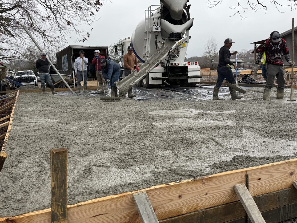 Son Concrete crew screeding a freshly poured slab from a mixer truck